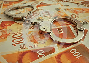 Handcuffs on the background of the 100 money of shekels