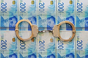 Handcuffs on the background of the 200 money of shekels