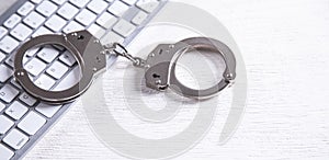 Handcuffs on computer keyboard. Concept of Cyber crime and Online fraud