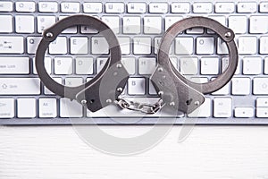 Handcuffs on computer keyboard. Concept of Cyber crime and Online fraud