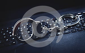 Handcuffs on computer keyboard. Concept of Cyber crime and Online fraud