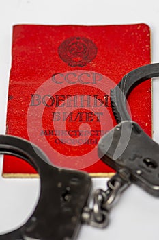 Handcuffs are depicted on a white background on a Russian military ticket. Translation into Russian: USSR, Military ID, Ministry o