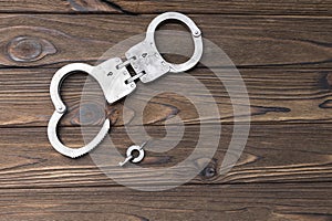 Handcuffs for detaining criminals, key, on a wooden background