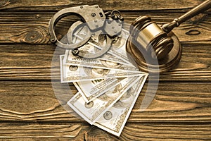 Handcuffs, dollar bills, a judge`s hammer against the background