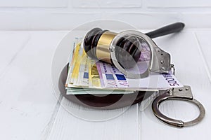 Handcuffs with euro banknotes and judge`s gavel