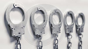 The handcuffs hang in a row on a chain on the wall