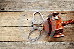 Handcuffs and judge gavel on wooden background suggesting starting a crime trial verdict photo