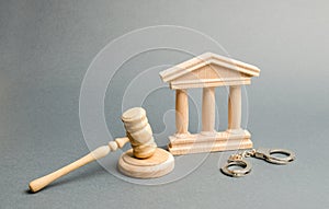 Handcuffs, judge`s gavel and courthouse. Protection of the defendant in the criminal case. Protection strategy. verdict photo