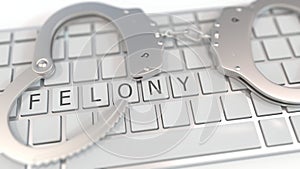 Handcuffs on keyboard with FELONY text. Computer crime related conceptual 3D rendering