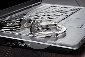 Handcuffs on laptop cyber crime concept photo