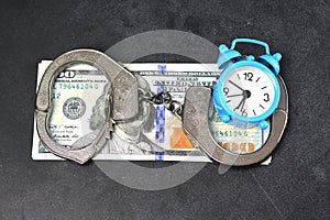 Handcuffs, money and alarm clock on dark background, bail concept