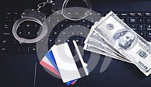 Handcuffs, money, credit cards on computer keyboard. Concept of Cyber crime and Online fraud