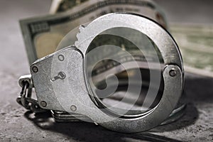 Handcuffs and one hundred dollar bill on the table. Concept on the topic of fraudulent transactions with money entails punishment