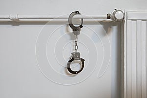 Handcuffs on the radiator. Police handcuffs and collar
