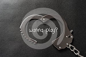 Handcuffs shaped like a heart on black and writtting with wanna play