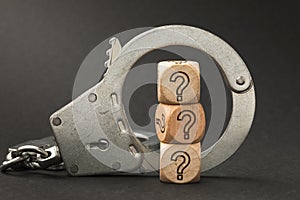 Handcuffs and wooden cubes with a question mark, guilt determination concept