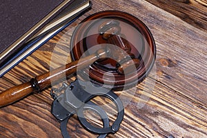 Handcuffs and a wooden gavel in front of manila folders
