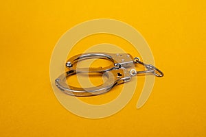 Handcuffs on yellow background, concept of arrest