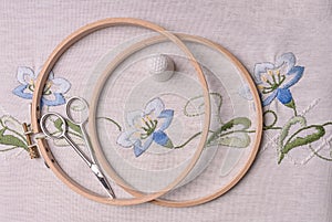 Handemade embroidery. The cloth, thimble, scissors, embroidery hoop. Blue flowers