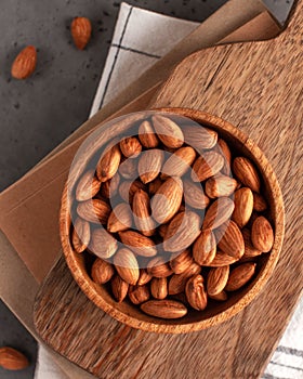 A handful of almonds on a wooden plate. Healthy snack on the background of a wooden Board and a kitchen towel