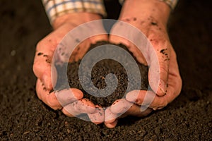 Handful of arable soil in hands of responsible farmer