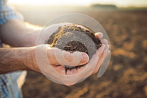 Handful of arable soil in hands of responsible farmer photo