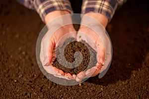 Handful of arable soil in hands of responsible farmer photo