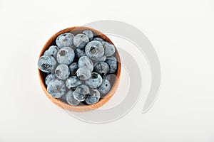 Handful of blueberries in wooden bowl isolated on white