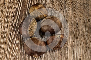 Handful of brown edible chestnut on a wooden table