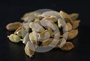 A handful of cardamon seeds on a black table