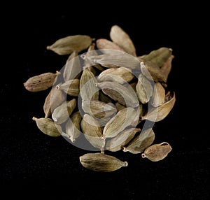 A handful of cardamon seeds on a black table