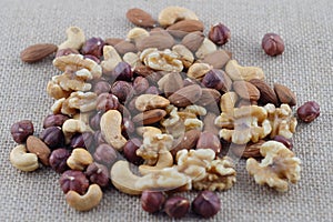Handful of cashew nuts, almonds, walnuts and hazelnuts on a burlap fabric. Selective focus.