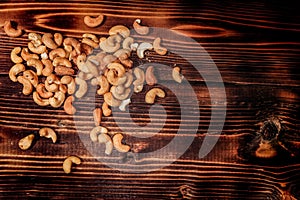 A handful of cashews are scattered on a wooden table. place for the inscription top view