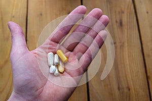 A handful of health supplements over wooden counter
