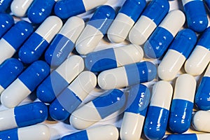 A handful of pills close-up. Capsules medications white and blue. Neer