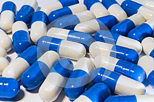 A handful of pills close-up. Capsules medications white and blue. Neer