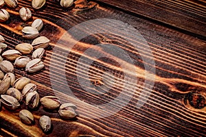 A handful of Pistachio nuts are scattered on a wooden table. place for the inscription