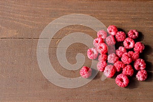 A handful of ripe, fresh, wild raspberries on a dark brown wooden Board