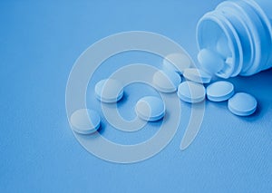 A handful of white large tablets on a blue background, vitamins
