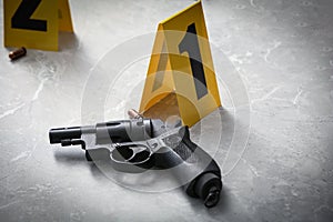 Handgun and crime scene marker on light grey marble table
