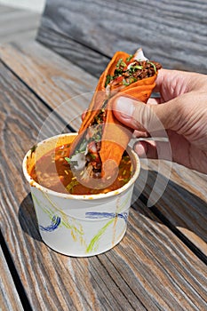Handheld Birria Taco Dipped into a Side of Consomme