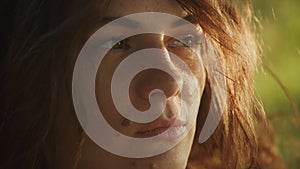 Handheld close up catching sunbeam on curly caucasian woman face with freckles and birthmarks outside