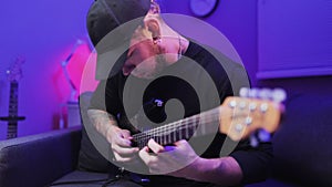 Handheld close-up shot of the virtuoso guitarist plays the electric guitar and quickly moves fingers on the guitar neck.