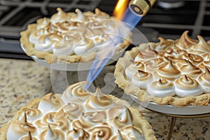 handheld kitchen torch browning meringue on individual pies photo