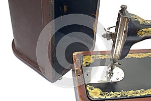 Handheld sewing machine, in front of vintage wooden case cover