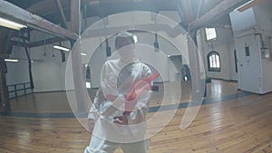 Handheld shot of focused girl showing karate movements in gym