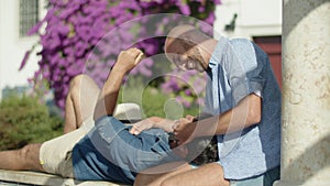 Handheld shot of gay lying on his lovers knees in public garden