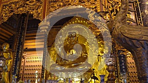 A handheld shot of the golden sitting Buddha statue in the Bai Dinh pagoda in Ninh Binh Vietnam's largest temple complex