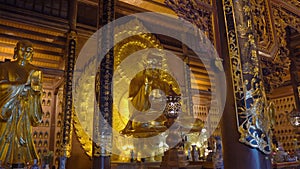 A handheld shot of the golden sitting Buddha statue in the Bai Dinh pagoda in Ninh Binh Vietnam's largest temple complex