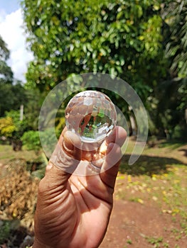 Handholding a crystal ball on blurred nature background